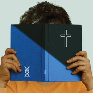 A child covers its face by holding up a blue book with a cross on the front cover and a DNA symbol on the back cover.