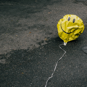 A deflated smiley-faced balloon in the street