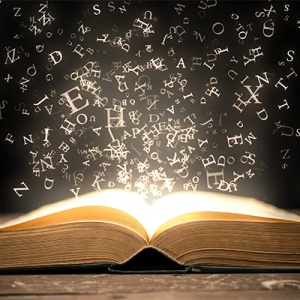 A glowing book on a table with letters bursting out of it and floating in the air.