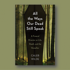 Book cover: A black background in the shape of a coffin is framed by a green light silhouetting trees with brown trunks and no branches in the shape of curtains; white text on black reads "All the Ways Our Dead Still Speak"