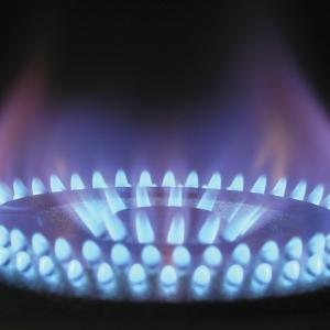 A close-up of the ignited blue flame of a gas cooktop.