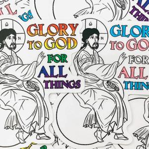 An illustration of Jesus sitting on a globus cruciger as he raises his hand to text that reads, "Glory to God for all things." One version depicts the text in the colors of the LGBT Pride flag and the other the colors of the transgender flag.
