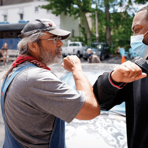 A Black man and a white man "high-fiving" each other with their elbows.