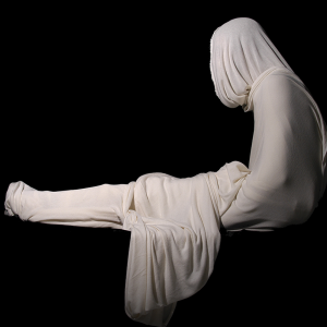 A marble statue of a person with silky fabrics draped over their waist and head.