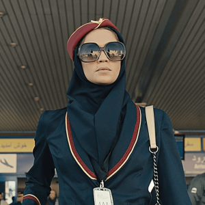 A spy dressed as a flight attendant with sunglasses exits the Tehran airport