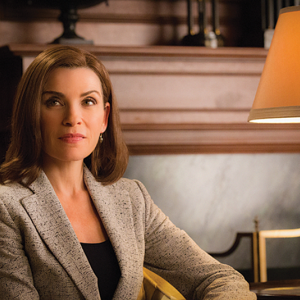 Julianna Margulies as Alicia Florrick in 'The Good Wife.' She has shoulder-length brown hair, wears a gray blazer, and is sitting in a chair slightly offscreen, with a lamp off to her left.