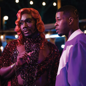 Uncle Clifford (Nicco Annan), the owner of The Pynk strip club, stands beside Lil' Murda (J. Alphonse Nicholson) as they look off in the distance.