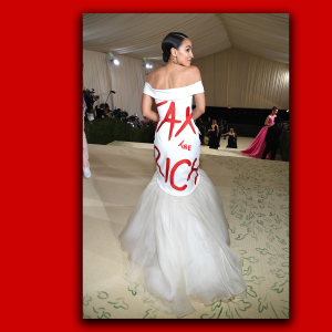 Alexandria Ocasio-Cortez stands with her back to the camera, displaying a ball gown that says "Tax the Rich."