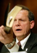 Justice Roy Moore holds a Bible while testifying in a hearing, 2004. Via Getty Images. Justice Roy Moore holds a Bible while testifying in a hearing. Via Getty Images.