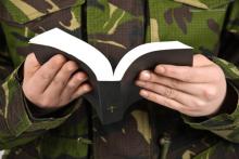Army soldier reading bible ,selective focus on book and hands. Photo courtesy Blaj Gabriel/shutterstock.com. Photo courtesy Blaj Gabriel/shutterstock.com.