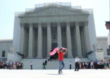 A man exits the Supreme Court building with an American flag after its rulings on same-sex marriage. RNS photo: Adelle M. Banks