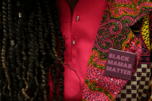 A woman with dreadlocks and a pink shirt wears a purple pin says "Black Mamas Matter"