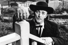 Harry Powell, played by actor Robert Mitchum, with his hands on a fence, showing LOVE tattooed on his knuckles.