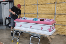 A worker decorates a pink-and-white casket with a TikTok symbol