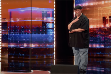 Richard Goodall putting his hand on his chest as he performs on the America's Got Talent stage.