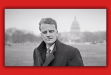Billy Graham looks straight into the camera with the US Capitol building behind him.