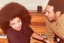 A young Nikky Finney sits at a piano with her father in 1972.