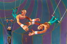 A painting featuring two members of the Flying Rodleighs flying in the air with Henri Nouwen holding onto a trapeze in the background.