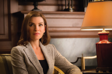 Julianna Margulies as Alicia Florrick in 'The Good Wife.' She has shoulder-length brown hair, wears a gray blazer, and is sitting in a chair slightly offscreen, with a lamp off to her left.