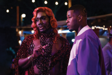 Uncle Clifford (Nicco Annan), the owner of The Pynk strip club, stands beside Lil' Murda (J. Alphonse Nicholson) as they look off in the distance.