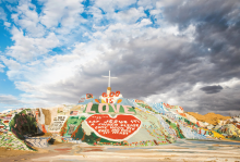 The image shows a large colorful hill with a cross on top that has a heart and says "God is Love" 