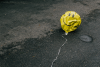 A deflated smiley-faced balloon in the street