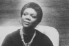 A black-and-white photo of poet Lucille Clifton, sitting in a chair wearing black robes and several layered necklaces.