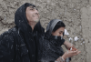 A husband and wife stand close to each other and enjoy falling snow