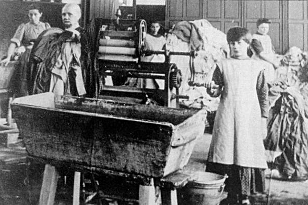 An old photograph of children and women are shown in a Magdalene laundry doing hard labor, of which they were forced to do without pay.